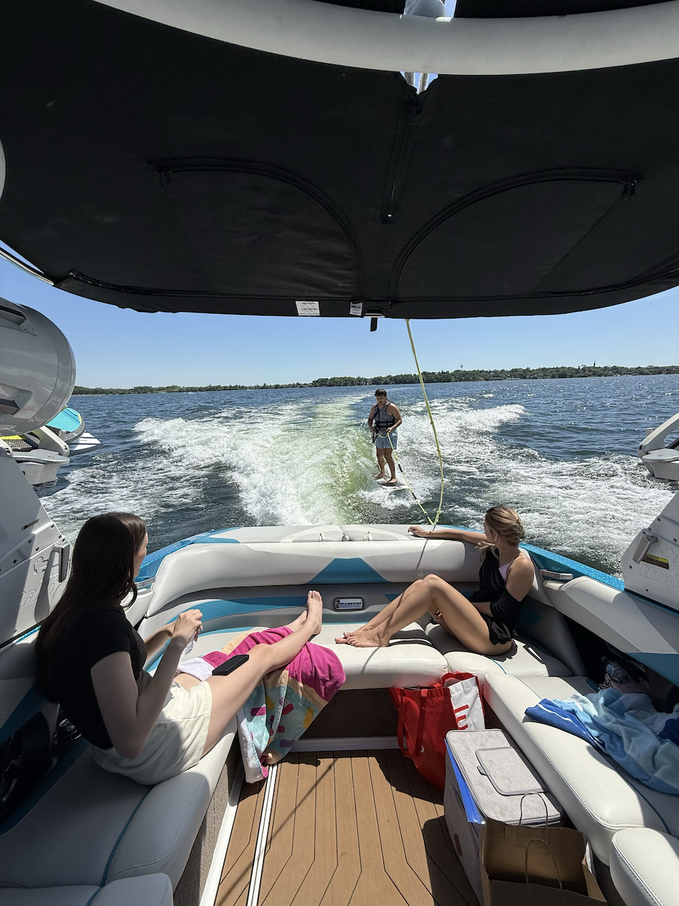 Guests relaxing on the boat while rider surfs